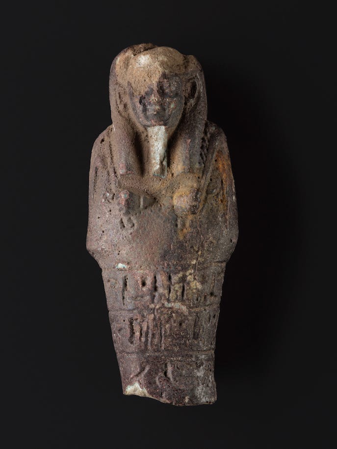 The upper half of an ancient Egyptian faience shabti, against a black background, dating to about 664-332 BC and found at a school in Scotland.