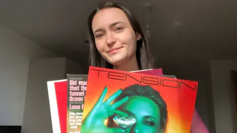 Bethan Currie Bethan Currie holding three vinyl records and smiling behind them.